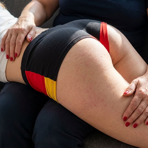 Junge Frau in Deutschland-Shorts über dem Knie versohlt
